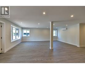 A spacious room with wooden flooring and white walls.