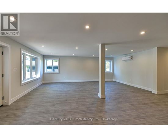 A spacious room with wooden flooring and white walls.