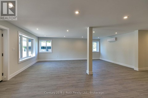 A spacious room with wooden flooring and white walls.