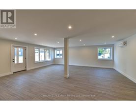 A spacious room with wooden flooring and white walls.