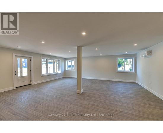 A spacious room with wooden flooring and white walls.