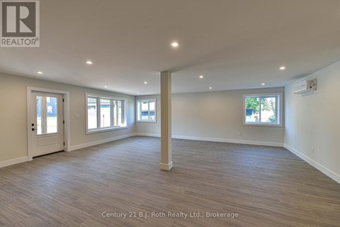 A spacious room with wooden flooring and white walls.