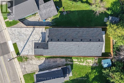 An aerial view of a building with a grey roof and a blue container in front of it.