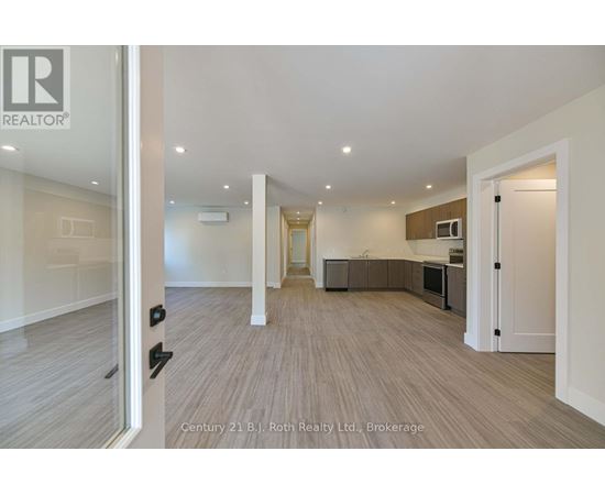 A spacious living room with a kitchen area in the background.