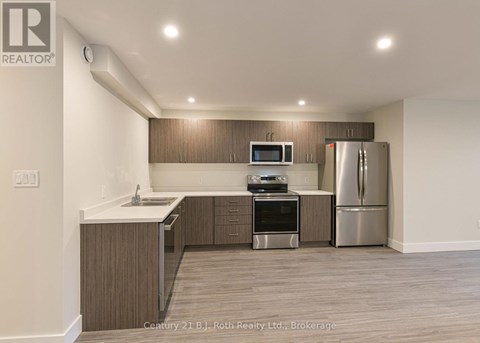 A kitchen with a refrigerator, oven, and microwave.