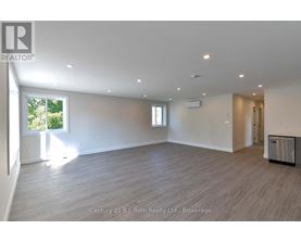 A spacious room with a large window and a door leading to another room.