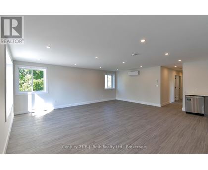 A spacious room with a large window and a door leading to another room.