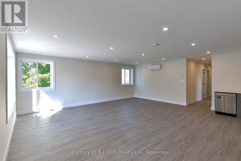 A spacious room with a large window and a door leading to another room.