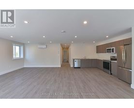 A spacious kitchen with stainless steel appliances and wooden flooring.