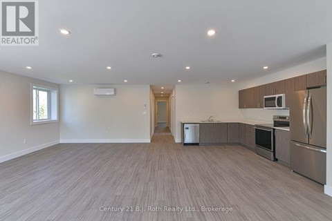 A spacious kitchen with stainless steel appliances and wooden flooring.