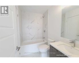 A white bathroom with a marble patterned shower and toilet.