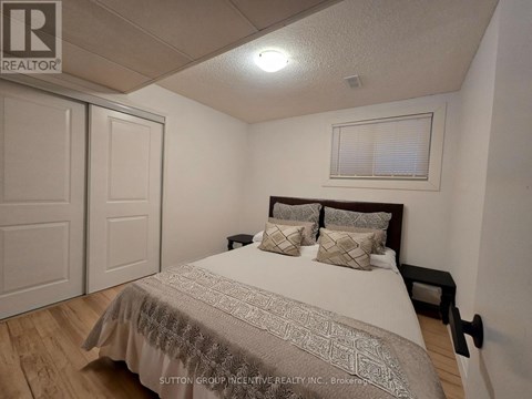 A bedroom with a bed, pillows, and a window with blinds.