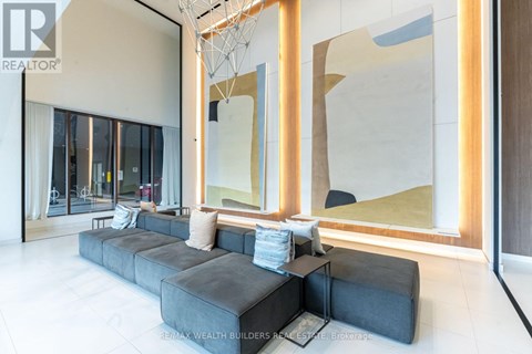A modern living room with a large grey sofa and a large abstract painting on the wall.