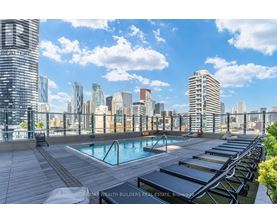 A pool area with sun loungers and a view of the city skyline.