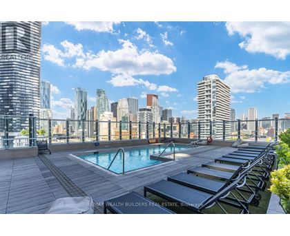 A pool area with sun loungers and a view of the city skyline.