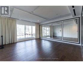 A spacious room with wooden floors and large windows.