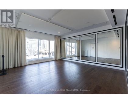 A spacious room with wooden floors and large windows.