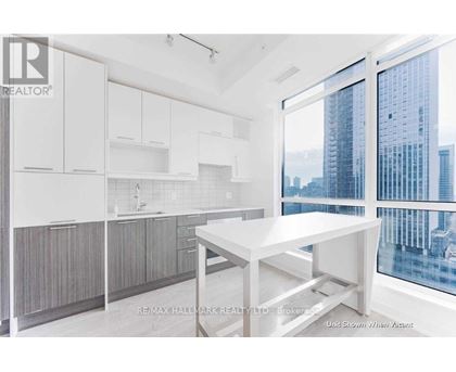 A white kitchen with a table and a window overlooking a city.