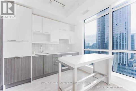 A white kitchen with a table and a window overlooking a city.