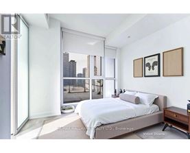 A bedroom with a large bed, a nightstand, and a window overlooking a cityscape.