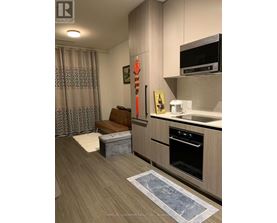 A kitchen with a wooden floor and a grey wall.