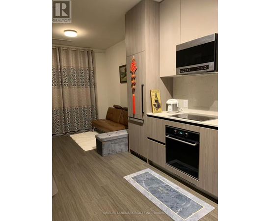 A kitchen with a wooden floor and a grey wall.