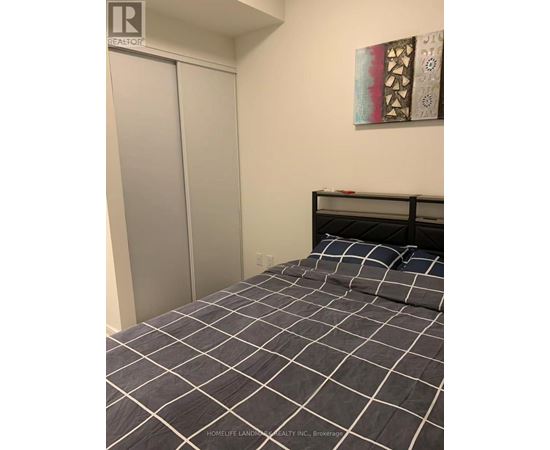 A bedroom with a bed and a painting on the wall.