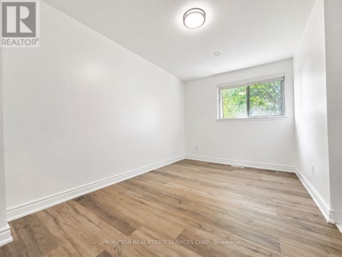 A room with wooden flooring and a window letting in natural light.