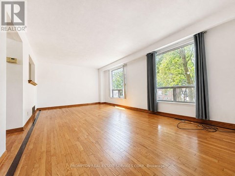 A room with wooden flooring and a window with a view of trees.