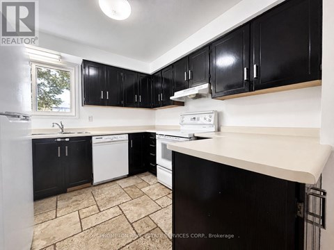 A kitchen with black cabinets and a white dishwasher.