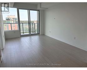 A large empty room with a view of a building outside the window.