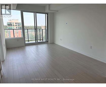 A large empty room with a view of a building outside the window.