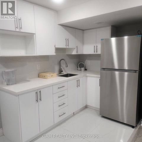 A kitchen with white cabinets and a stainless steel refrigerator.