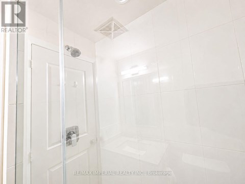 A white tiled bathroom with a glass shower door.