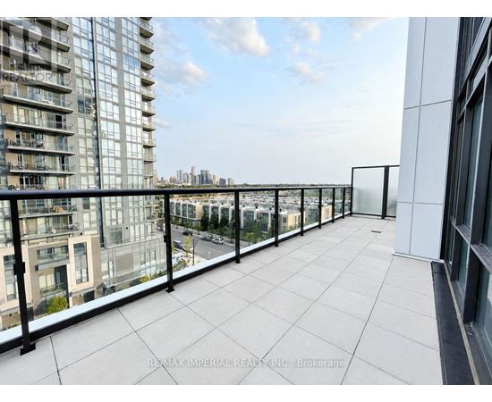 A balcony with a glass railing overlooks a cityscape.