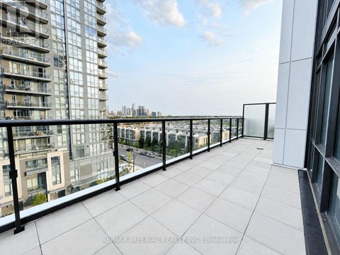 A balcony with a glass railing overlooks a cityscape.