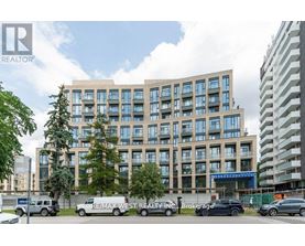 A modern multi-story building with a parking lot in front.