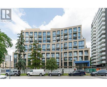 A modern multi-story building with a parking lot in front.
