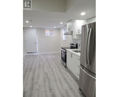 A kitchen with a refrigerator, oven, and cabinets.