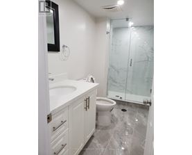 A white bathroom with a marble floor and a glass shower door.