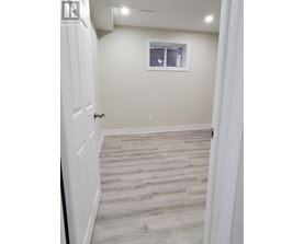 A hallway with wooden flooring and white walls.