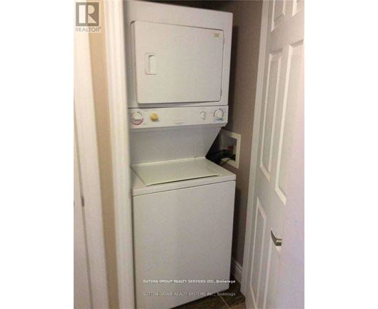 A white dishwasher and dryer are stacked in a small space.