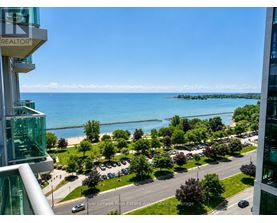 A view from a high-rise building overlooking a parking lot, trees, and a body of water.