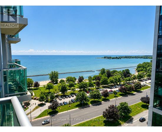 A view from a high-rise building overlooking a parking lot, trees, and a body of water.