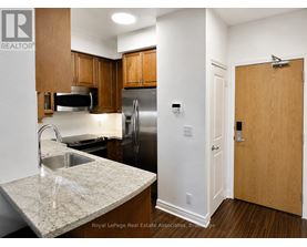 A kitchen with a sink, refrigerator, and cabinets.