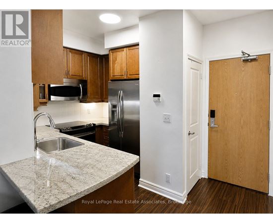 A kitchen with a sink, refrigerator, and cabinets.