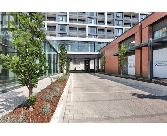 A long walkway with a tree on the left and a building on the right.