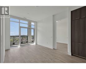 A spacious room with a large window and a wooden floor.