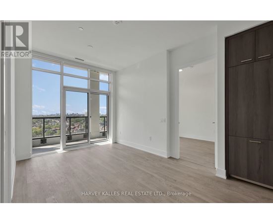 A spacious room with a large window and a wooden floor.