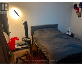 A bedroom with a bed, desk, and lamp.
